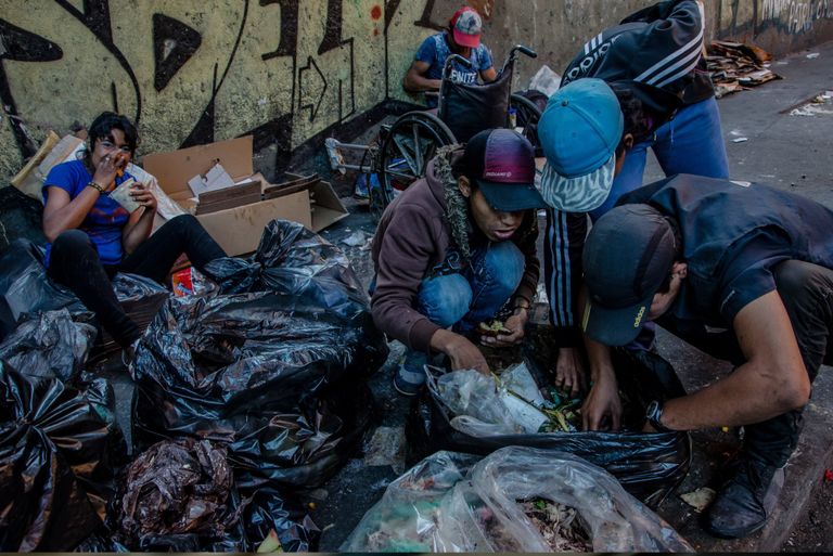 أطفال يبحثون عن الطعام في القمامة متجر يغلق بواباته جزئيا كإجراء وقائي ضد النهب في فنزويلا