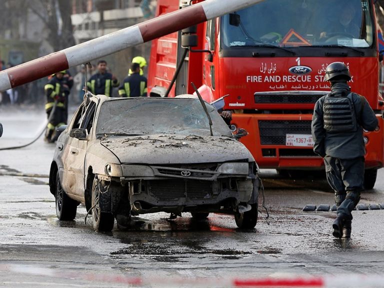 سيارة تضررت بشدة فى موقع الانفجار قوات الجيش والشرطة الأفغانية في موقع التفجير الإرهابي - أ.ف.ب