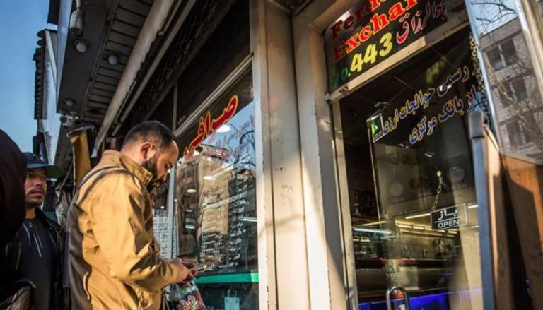 إيراني يتابع سعر الريال أمام أحد مكاتب الصرافة في طهران