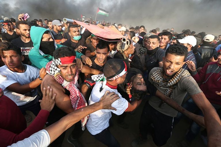 شبان يحملون أحد المصابين شباب من المشاركين في جمعة