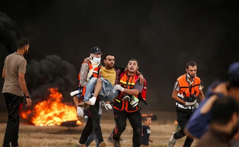 شبان يحملون مصابا مواجهات بين فلسطينيين وجنود الاحتلال - أ.ف.ب