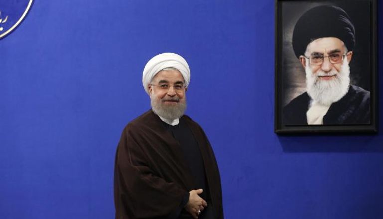 رئيس الحكومة الإيرانية حسن روحاني ووراءه صورة مرشد إيران
