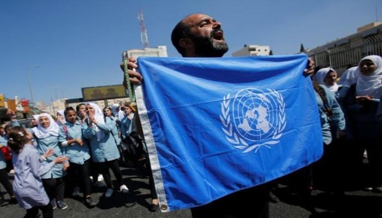 متظاهر فلسطيني يرفع علم الأمم المتحدة بمسيرة احتجاجية- أرشيفية