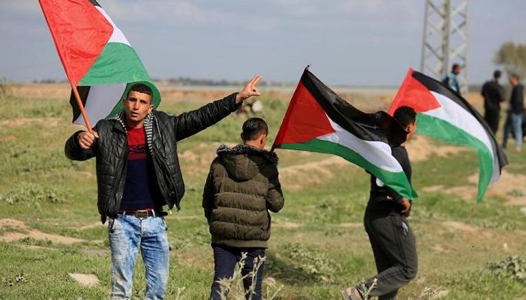 شباب يحملون الأعلام الفلسطينية في مسيرة بغزة- أرشيفية
