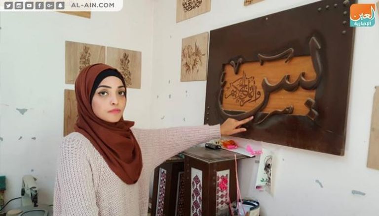 الفنانة الفلسطينية ولاء أبوالعيش أمام إحدى لوحاتها