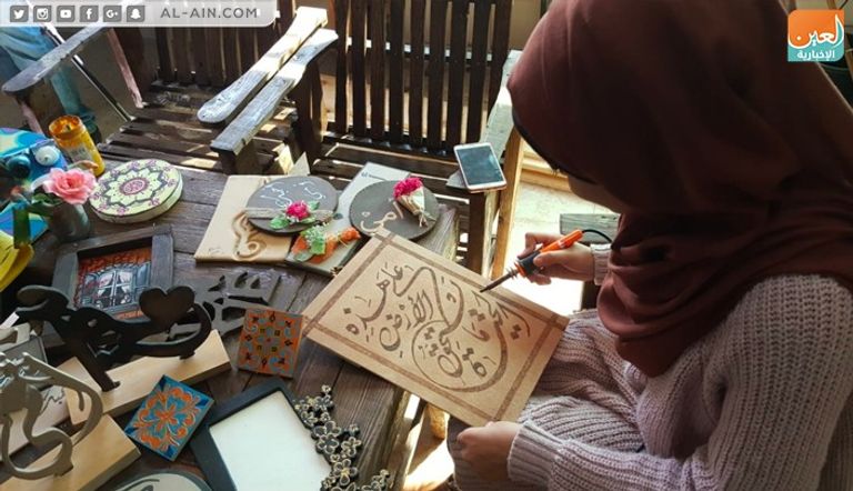 الفنانة الفلسطينية ولاء أبوالعيش أمام إحدى لوحاتها