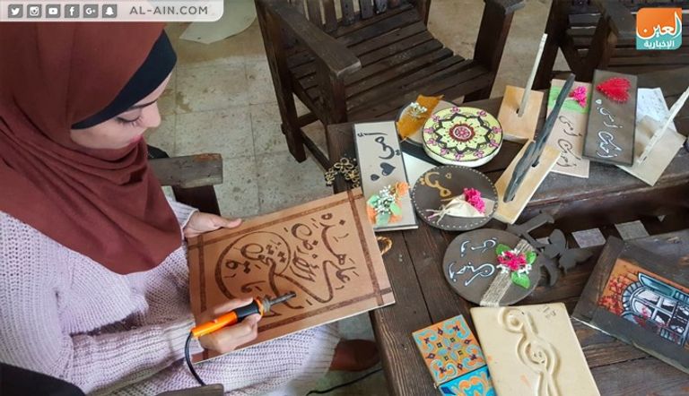 الفنانة الفلسطينية ولاء أبوالعيش أمام إحدى لوحاتها