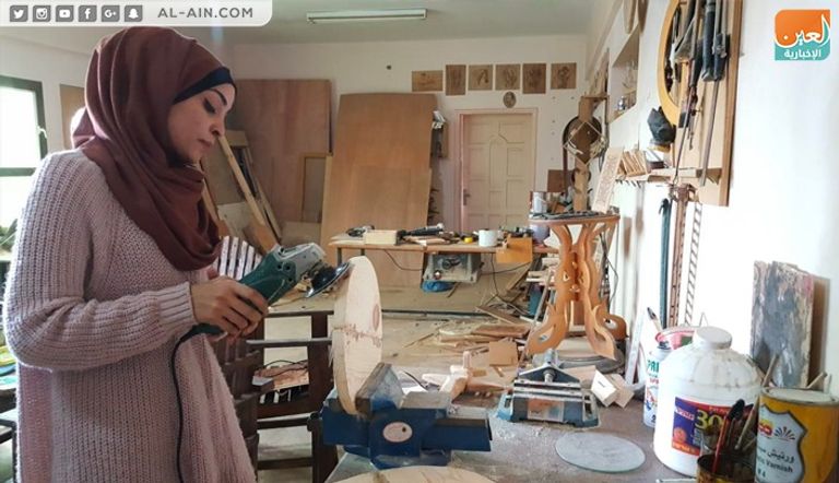 الفنانة الفلسطينية ولاء أبوالعيش أمام إحدى لوحاتها