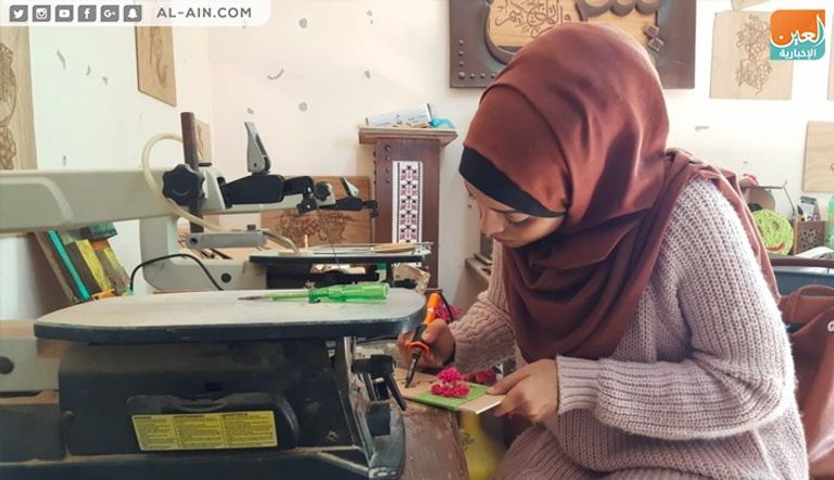 الفنانة الفلسطينية ولاء أبوالعيش أمام إحدى لوحاتها