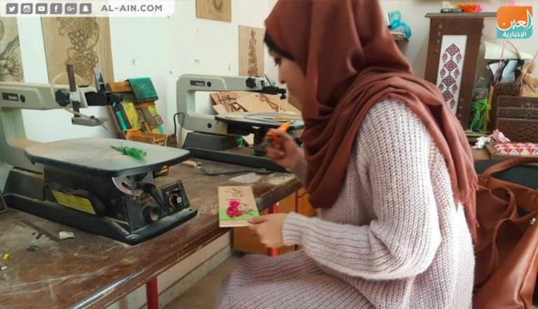 الفنانة الفلسطينية ولاء أبوالعيش أمام إحدى لوحاتها