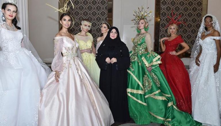 المصممة الإماراتية منى المنصوري تتوسط فتيات يرتدين تصميماتها