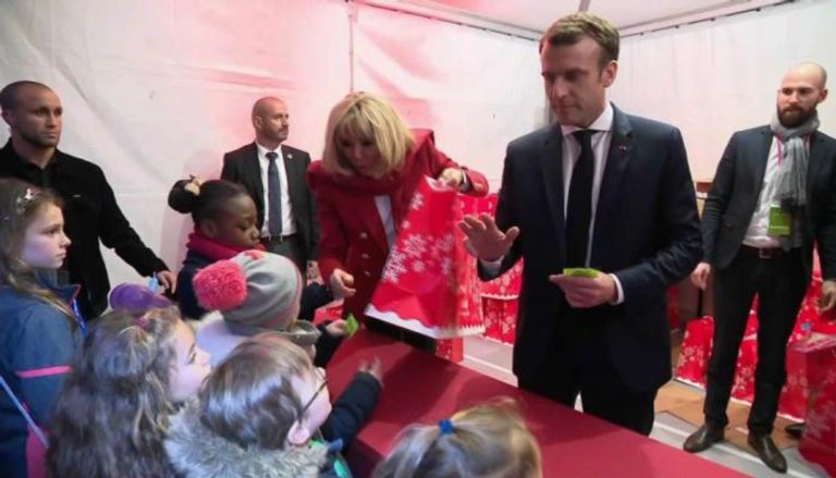 الرئيس الفرنسي إيمانويل ماكرون وزوجته برجيت خلال تسليم الهدايا للأطفال