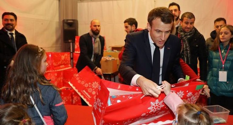 الرئيس الفرنسي إيمانويل ماكرون وزوجته برجيت خلال تسليم الهدايا للأطفال