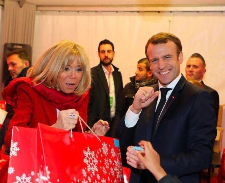 الرئيس الفرنسي إيمانويل ماكرون وزوجته برجيت خلال تسليم الهدايا للأطفال