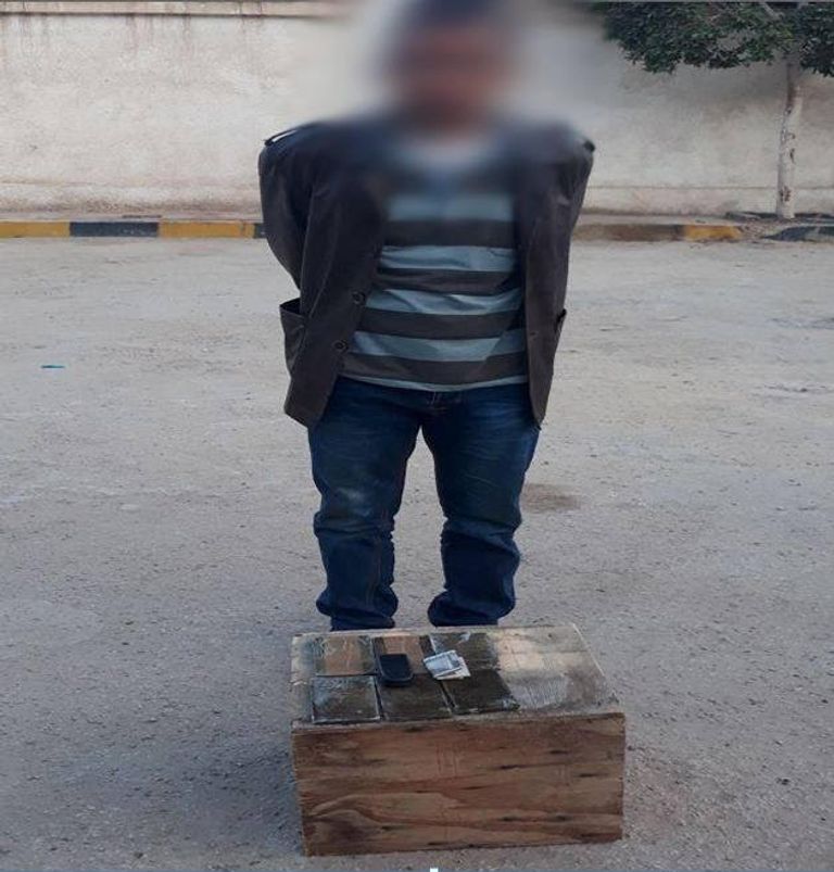 المتهم بعد القبض عليه جنديان مصريان أمام الأسلحة المضبوطة