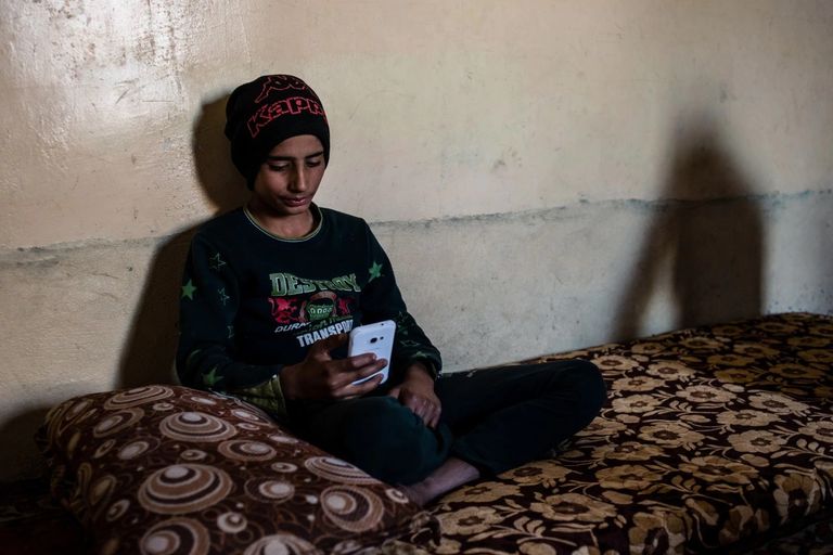 الطفل أحمد جاسم يقضي معظم وقته مع هاتفه الذكي  مبان دمرت جراء الاشتباكات في الموصل