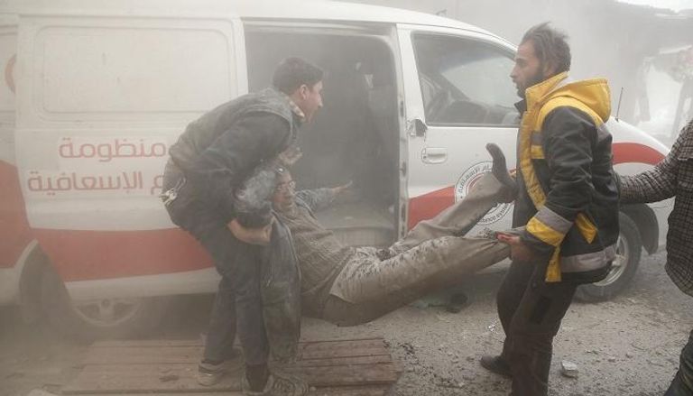 أحد الجرحى محمولًا وسط الغبار بعد غارة جوية في الغوطة الشرقية- رويترز