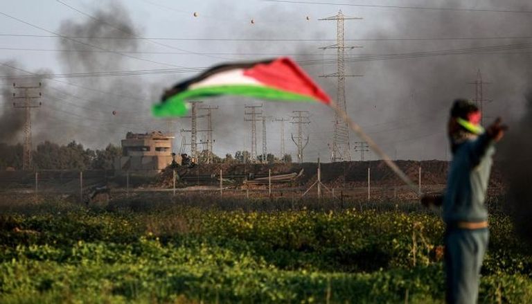 شاب فلسطيني يرفع العلم قرب حدود غزة