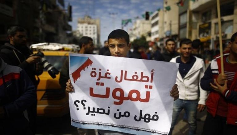 شاب فلسطيني يرفع لافته أثناء إضراب غزة
