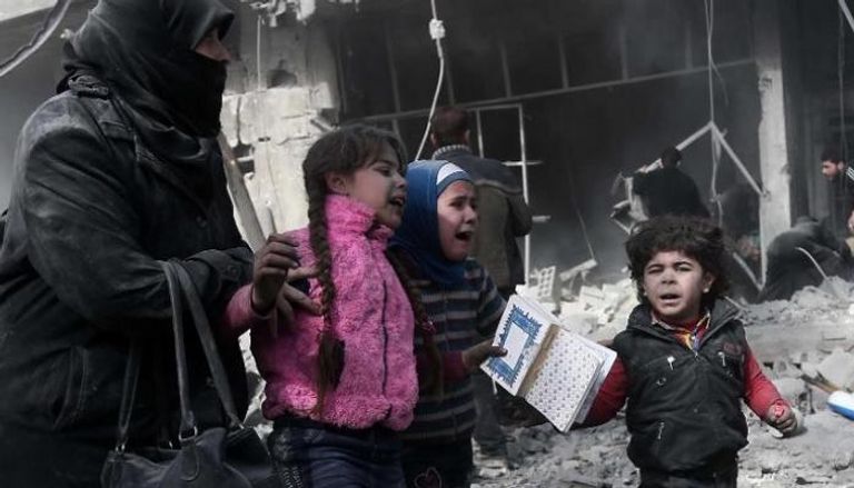 سيدة تحاول الفرار بأطفالها بعد قصف طال حيا سكنيا في الغوطة الشرقية
