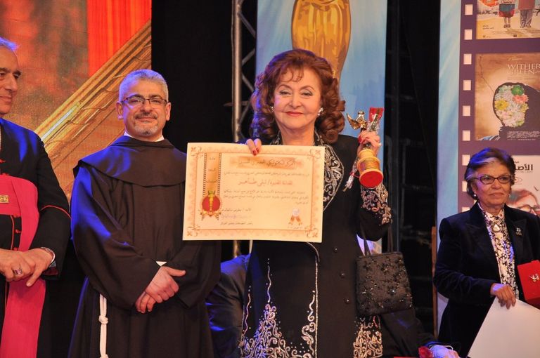 الفنانة ليلى طاهر إلى جوار لافتة المهرجان