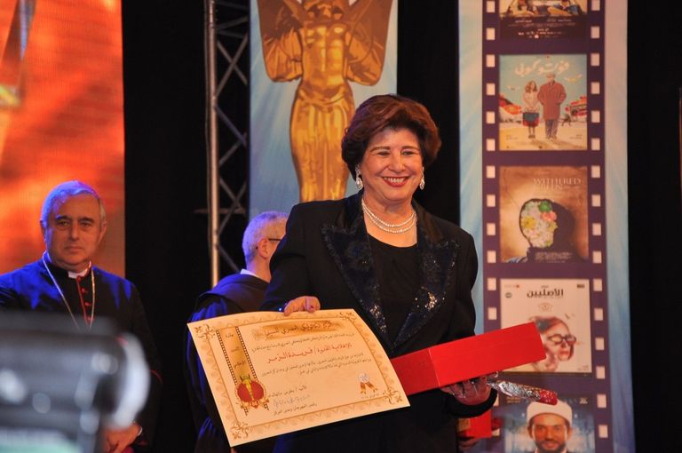 الفنانة ليلى طاهر إلى جوار لافتة المهرجان