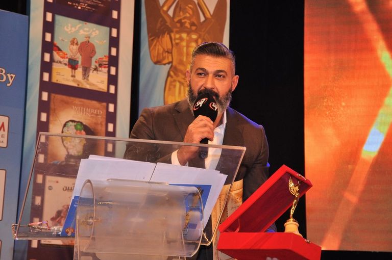 الفنانة ليلى طاهر إلى جوار لافتة المهرجان