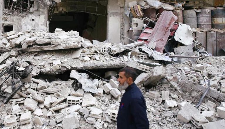 سوري يمر بجانب أحد المنازل المتهدمة في الغوطة بسوريا- (رويترز)