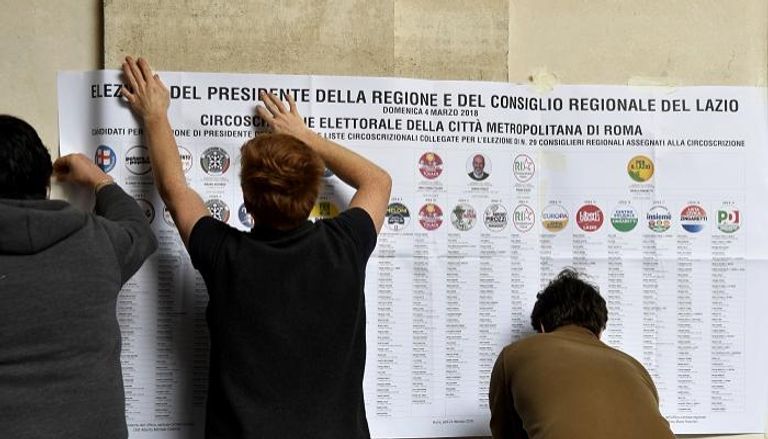 تعليق ملصقات انتخابية بأحد مراكز الاقتراع في إيطاليا - أ.ف.ب