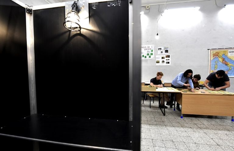 أحد مراكز الاقتراع في إيطاليا - أ.ف.ب تعليق ملصقات انتخابية بأحد مراكز الاقتراع في إيطاليا - أ.ف.ب