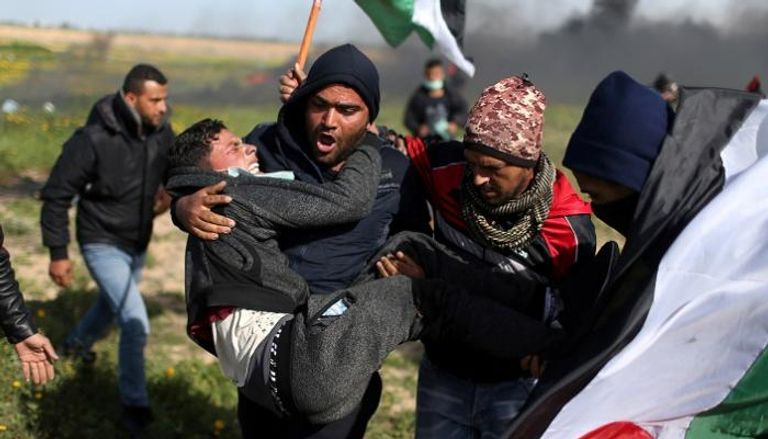 مجموعة من الشباب يحملون مصابا برصاص الاحتلال - رويترز
