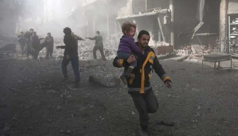سوري يحمل طفله هربا من ويل الحرب