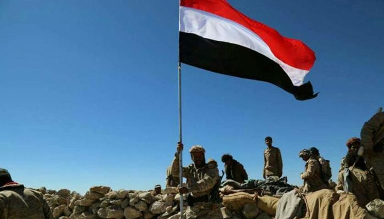 عناصر من الجيش اليمني يرفعون العلم بأحد المواقع المحررة في جبهة نهم