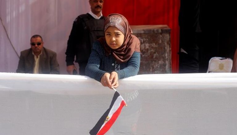 طفلة تحمل علم مصر أمام إحدى لجان التصويت