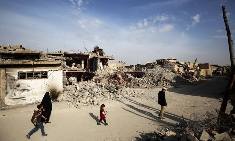 عراقيون يسيرون بجوار حطام المباني جانب من الدمار بالموصل القديمة