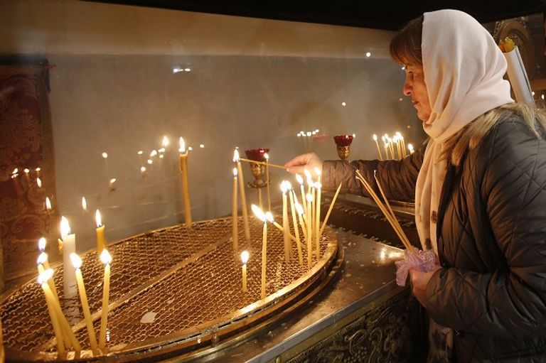 سيدة تضيء الشموع في كنيسة القيامة-أرشيفية  باب كنيسة القيامة وهو مغلق-أرشيفية