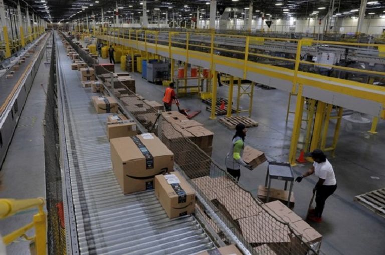 عامل يجمع العناصر لتسليمها في مركز توزيع أمازون في فينيكس صناديق أمازون مكدسة للتسليم في حي مانهاتن في مدينة نيويورك- رويترز