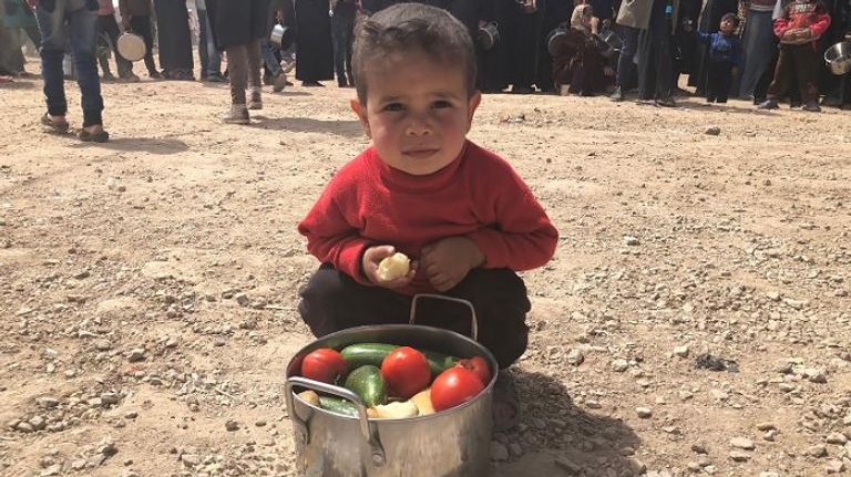 طفل سوري يضع أمامه وعاء الطعام حافلة تقل مدنيين سوريين