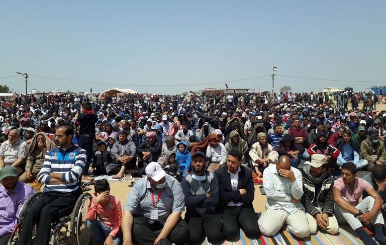 محتشدون فلسطينيون بمسيرة العودة الكبرى فلسطينيون يحملون متظاهرا مصابا خلال المسيرة