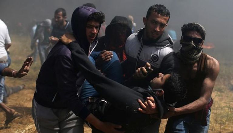مجموعة من الشبان يحملون فلسطينيا مصابا برصاص الاحتلال - رويترز