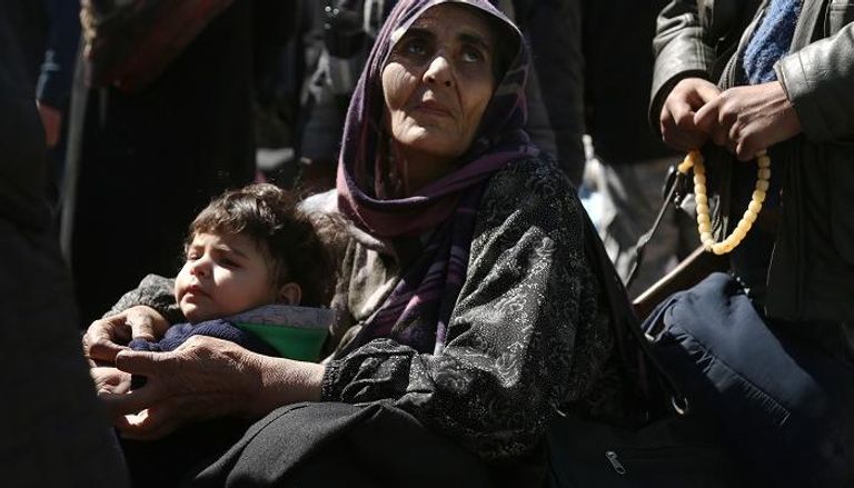 طفل مع امرأة سورية خلال عمليات الإجلاء من الغوطة الشرقية- أرشيفية