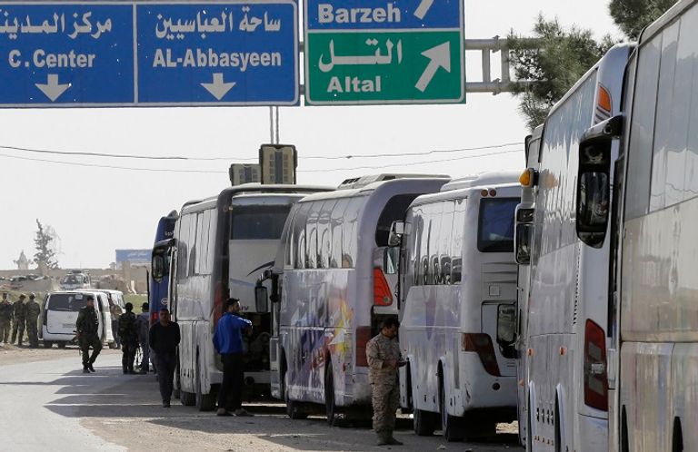 حافلات الإجلاء من الغوطة الشرقية- أرشيفية طفل مع امرأة سورية خلال عمليات الإجلاء من الغوطة الشرقية- أرشيفية