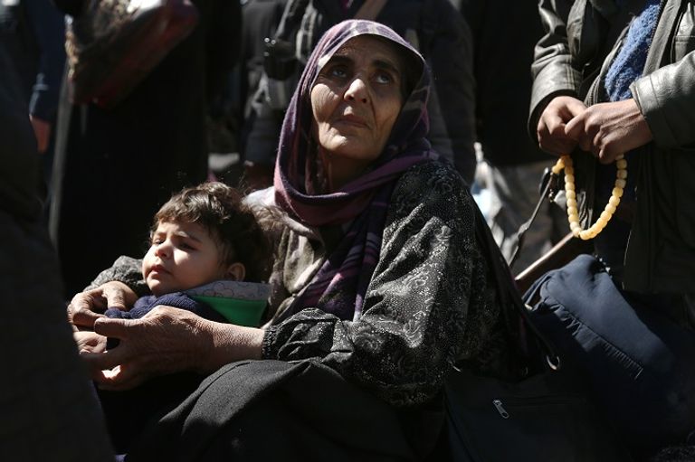 امرأة سورية مع طفلها خلال عمليات الإجلاء من الغوطة الشرقية- أرشيفية