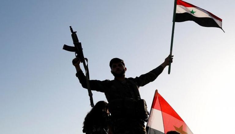 جندي سوري يرفع علم بلاده احتجاجا على الضربة الأمريكية (رويترز)