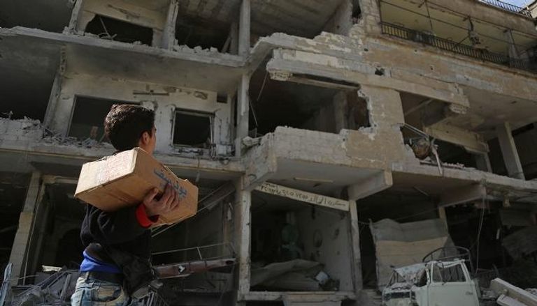 طفل سوري ينظر إلى مبنى مدمر جراء القصف في الغوطة الشرقية- أرشيفية