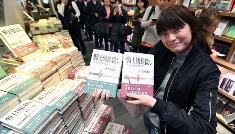  جمهور موراكامي يلتقطون صورا مع إحدى إصداراته فور طرحها بالمكتبات