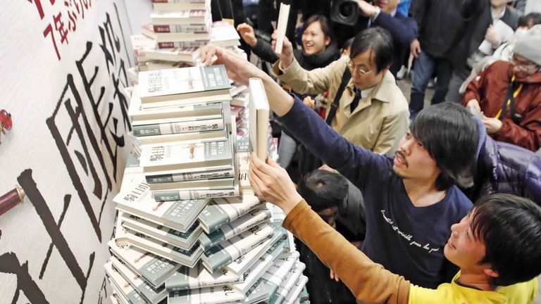  جمهور موراكامي يلتقطون صورا مع إحدى إصداراته فور طرحها بالمكتبات