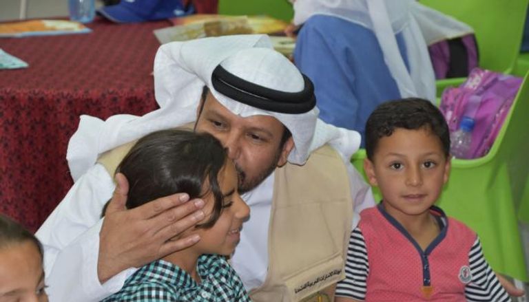 حمد العامري يقبل بعض أطفال اللاجئين في المخيم
