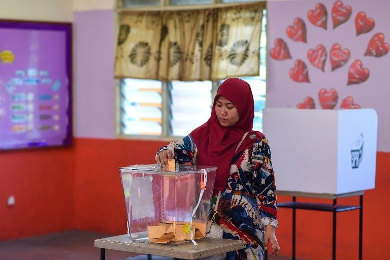 امرأة ماليزية تدلي بصوتها في الانتخابات (أ ف ب) مهاتير محمد يدلي بصوته في الانتخابات (أ ف ب)