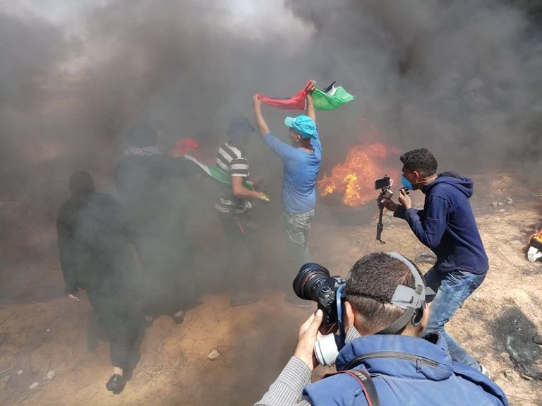 فلسطيني يحمل مصابا خلال الاشتباكات مع قوات الاحتلال